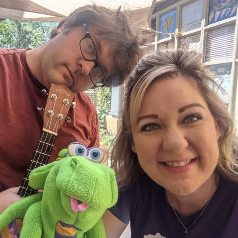 Man holding a guitar and woman holding a frog puppet