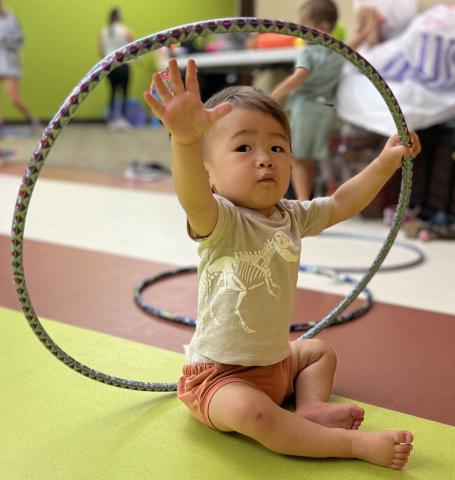 Boy toddler sitting and holding hoola hoop.