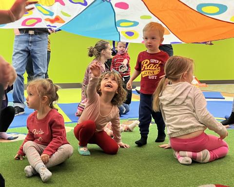 Children playing under a colorful parachute