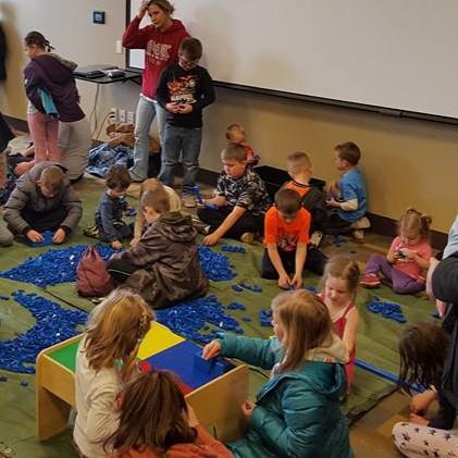 Children on floor building with LEGO blocks