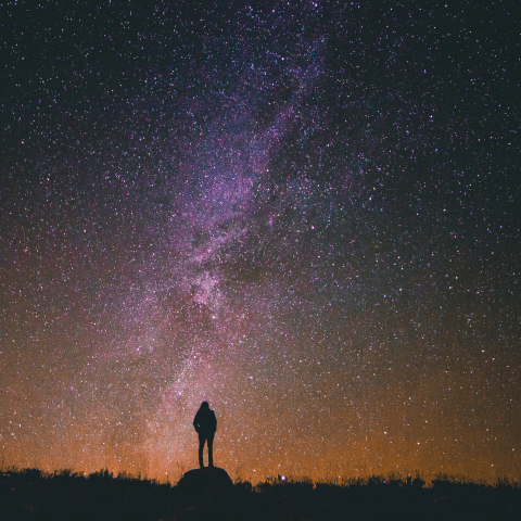 Person standing on a rock looking at the night sky