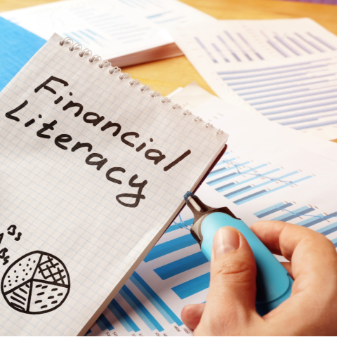 Financial literacy written on a notebook with graphs laying on a table underneath
