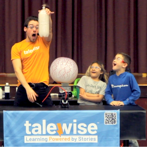 Excited man holding up a science experiment while a girl and boy look on expectantly