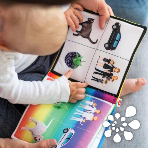 Baby with caregiver, reading a board book.