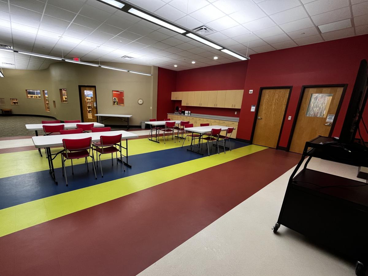 Program room set up with chairs and tables with sink and TV cart