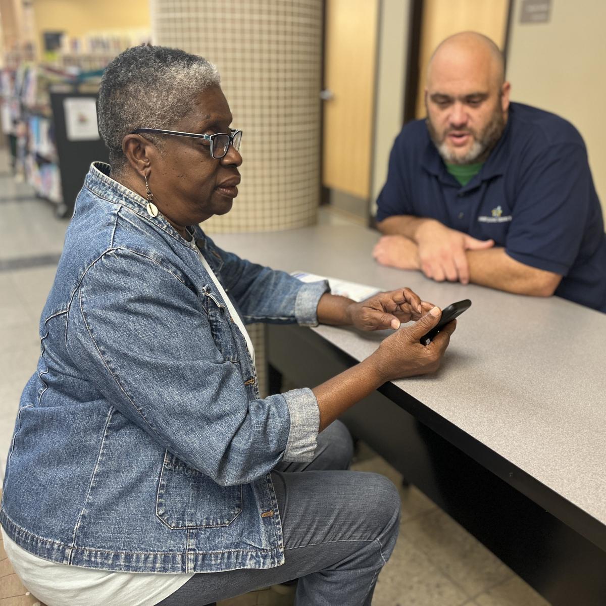 Woman with mobile phone getting help from staff