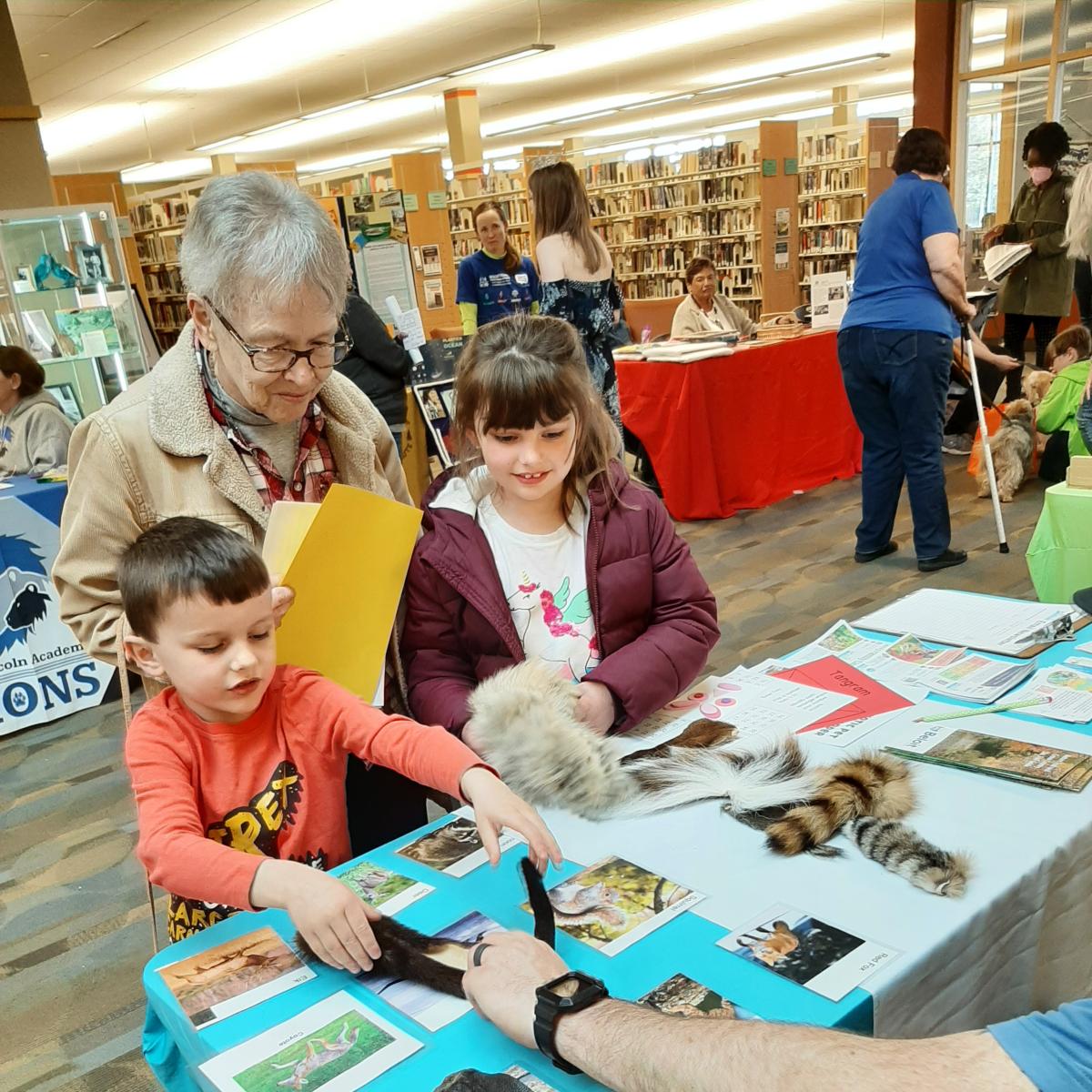 Two children interact with an exhibit while a caregiver looks on