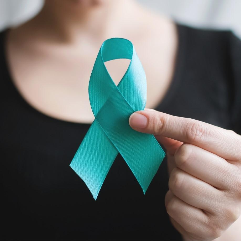 Woman's hand holding a teal ribbon