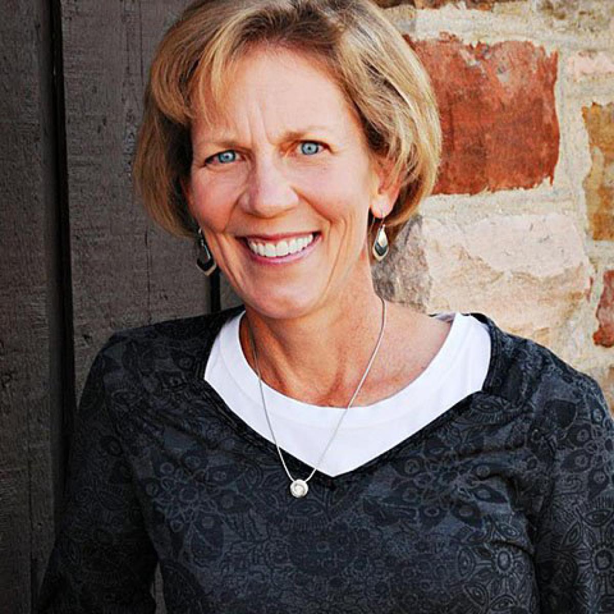 Posed photo of woman with bob-cut hair wearing a dark sweater with a white T-shirt underneath