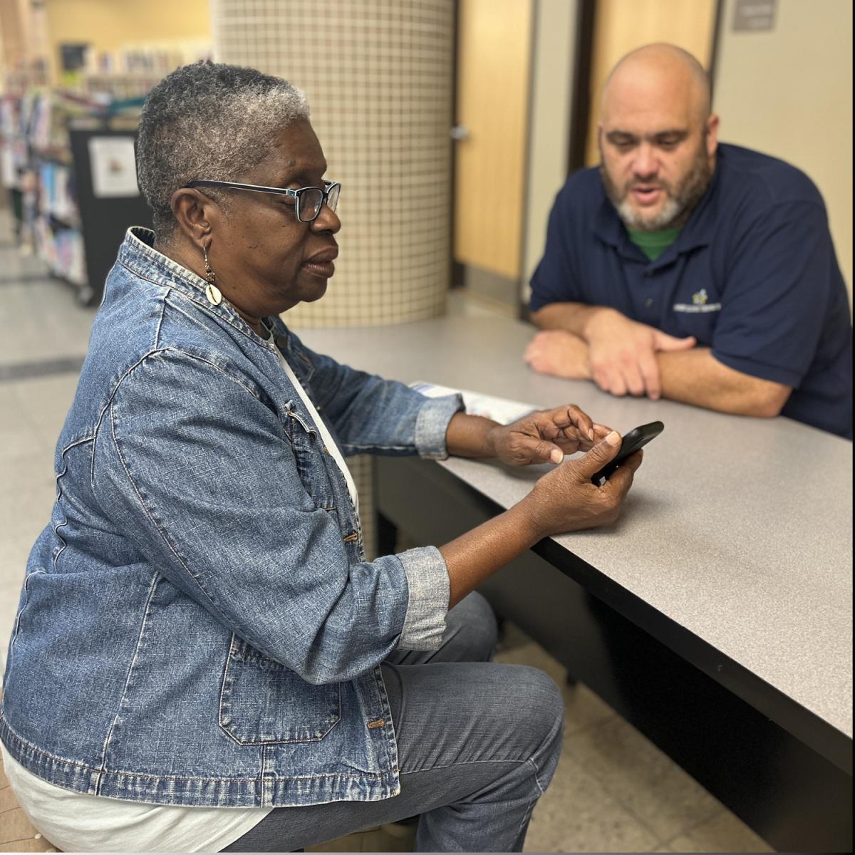 Woman with mobile phone getting help from staff