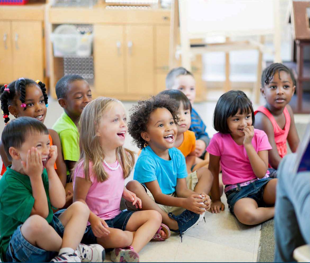 Children sitting on the floor smiling and listening intently