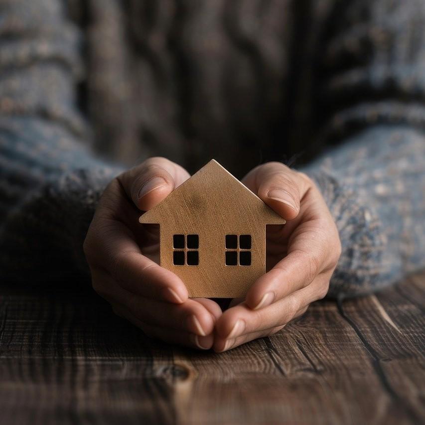 Hands holding a small wooden house