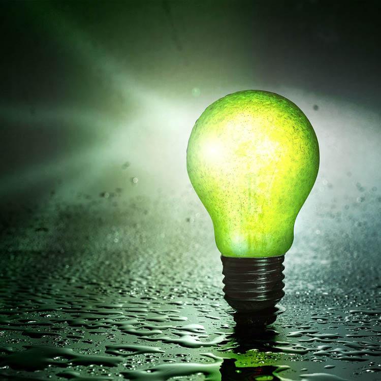 Glowing green lighbulb standing up on a wet ground