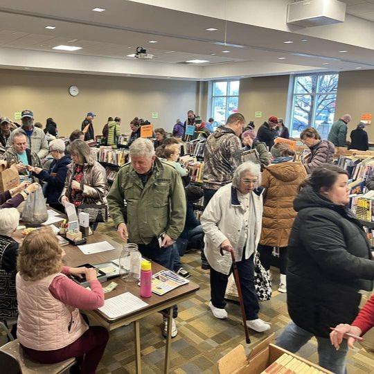 A crowded room of people browsing and buying books